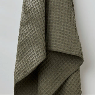Folded green textured blanket on a white background