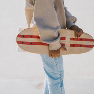 Person holding a skateboard with a red and white design against a light background