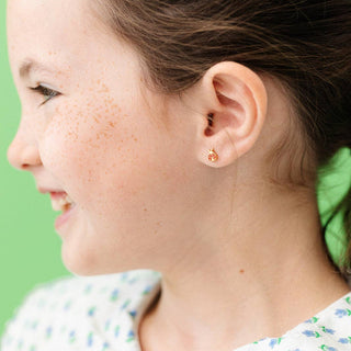 Close-up of a child's ear with a small earring against a green background