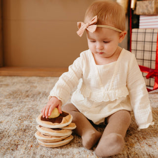 Child playing with a stack of wooden toys on a carpeted floor.