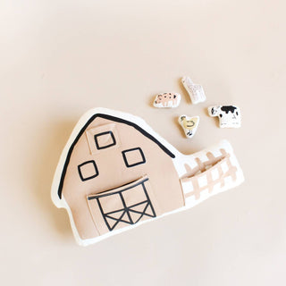 Barn-shaped cookie cutter with small animal cutouts on a beige background