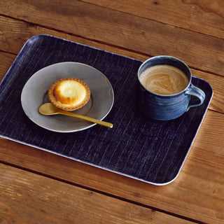 Cup of coffee and pastry on a blue placemat with a wooden background