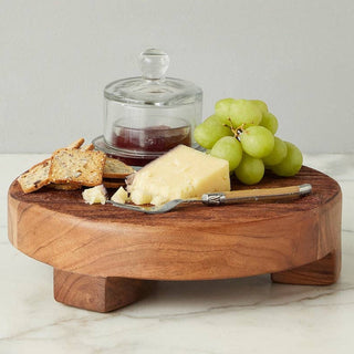 Wooden cheese board with cheese, grapes, and crackers on a marble surface.