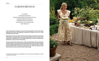 Woman in a garden setting with a table set for a garden brunch.