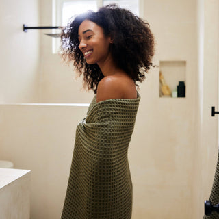 Woman wrapped in a green towel in a bathroom