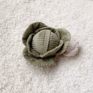 Green fabric cabbage baby rattle on a textured white background