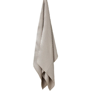 Beige textured towel hanging on a hook against a white wall