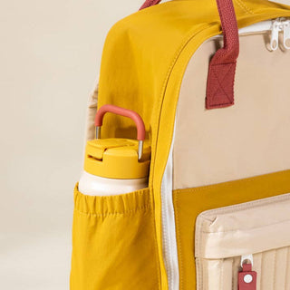 Yellow backpack with a water bottle in a pocket on a beige background