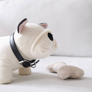 White plush dog toy with a black collar on a light gray background