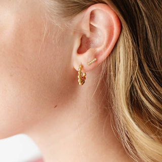 Close-up of a person wearing gold hoop earrings with a blurred background