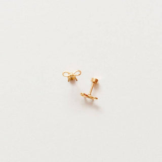 Gold earrings on a light gray background