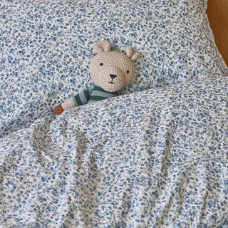 Small knitted bear toy on a floral blanket