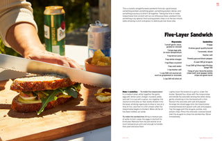 Person cutting a sandwich on a wooden board with a can of beer in the background.