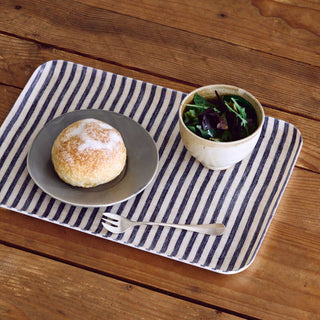 Placemat with a plate of bread and a bowl of salad on a wooden table