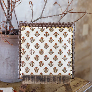 Decorative photo frame with floral pattern on a wooden surface with branches in the background