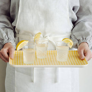 Person holding a tray with three glasses of lemonade.
