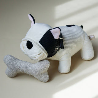 Stuffed animal toy resembling a cow with a bone on a light surface
