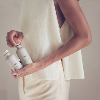Person holding two white bottles with a neutral background