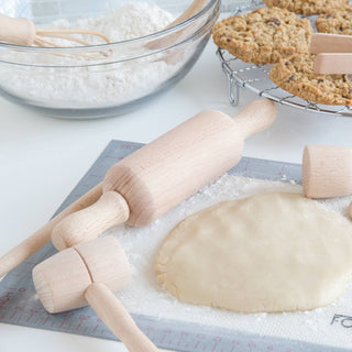Baking scene with dough, rolling pin, spatula, and cookies on a cooling rack.