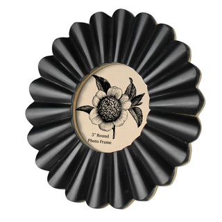A black scalloped round photo frame with a beige center label featuring a black floral illustration and the text '3" Round Photo Frame,' shown on a plain white background.