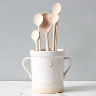 Ceramic container with wooden spoons on a gray background
