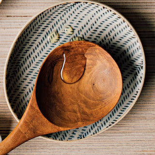Decorative ceramic plates with polka dots and textured patterns on a wooden surface, accompanied by a wooden spoon.