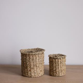 Two woven baskets on a wooden surface with a plain background