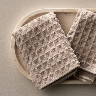 Textured brown towels on a beige plate against a neutral background