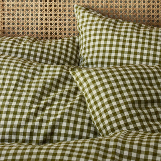 Green and white checkered bedding set on a bed with a woven headboard.