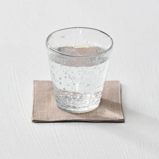Clear glass of water on a beige napkin with a white background