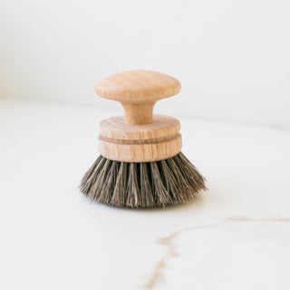 Wooden dish brush with bristle head on a white marble surface