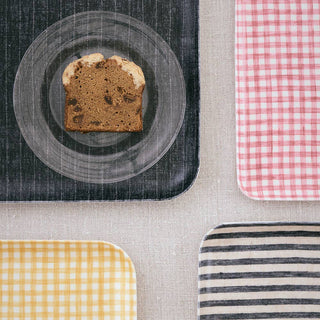Sliced loaf of bread on a plate with checkered and striped mats below