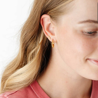 Close-up of a woman wearing gold earrings with a plain background