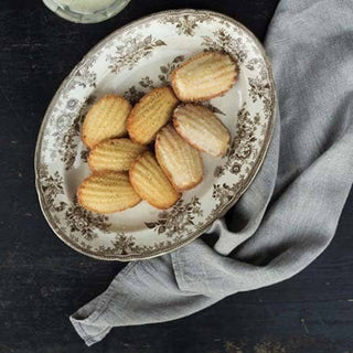 Decorative plate with madeleines on a dark surface with a gray napkin.