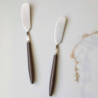 Two butter knives with wooden handles on a marble surface