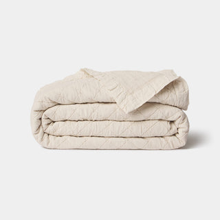 Folded beige quilt on a light gray background