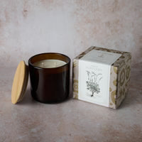 Brown candle with wooden lid and decorative box on a neutral background