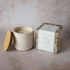 Beige ceramic jar with a lid and matching packaging box on a beige background