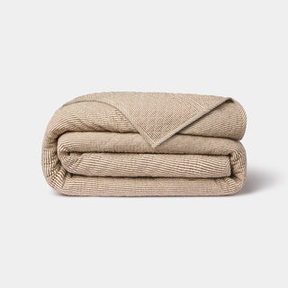 Folded beige blanket on a light gray background