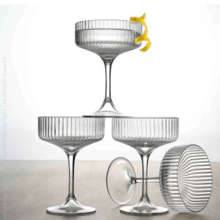 Set of clear glass cocktail glasses with a lemon twist on a light background