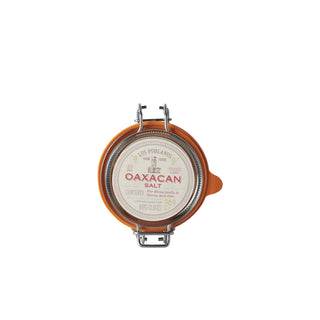 Oaxacan salt container with orange lid on a light gray background