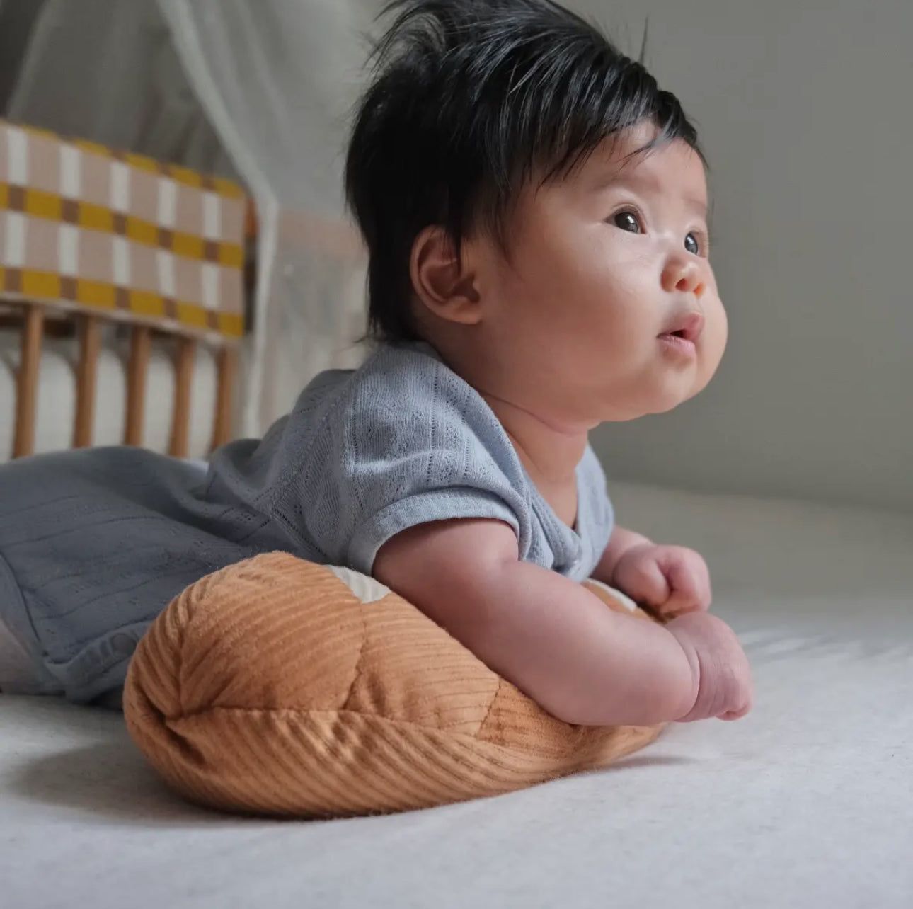 Baby lying on a soft bread pillow, looking up.
