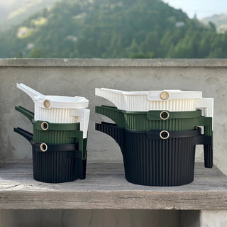 Stackable containers in green, white, and black on a wooden surface with a natural background.