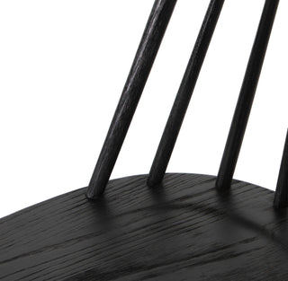 Close-up of a black chair with wooden legs on a white background