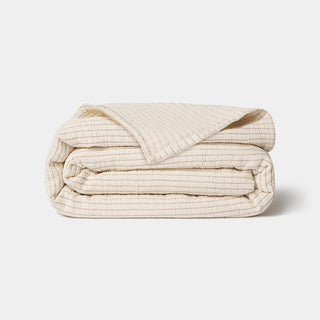 Folded beige quilt on a light gray background