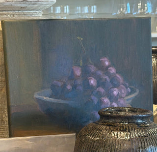 A rustic dark brown textured ceramic jar displayed on wooden cutting boards in a styled home decor setting, with paintings and vases in the background.