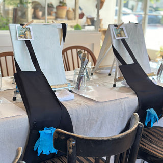 Dining area with chairs and tables set up, gloves on chairs, and a view of the outdoors.