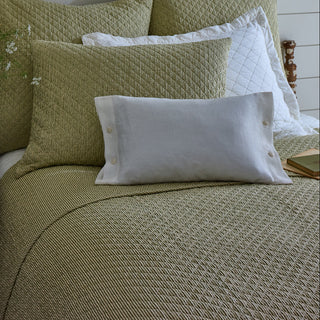 Bed with green textured bedding and pillows in a bedroom setting.