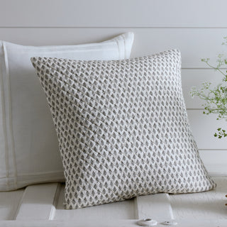 Textured pillow with geometric pattern on a white wooden surface