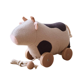Plush cow toy with wheels on a white background